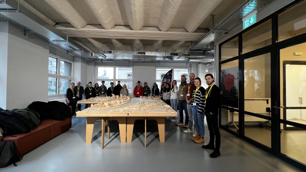 Photo de groupe autour d'une table avec une maquette d'une ville, en intérieur dans un bureau