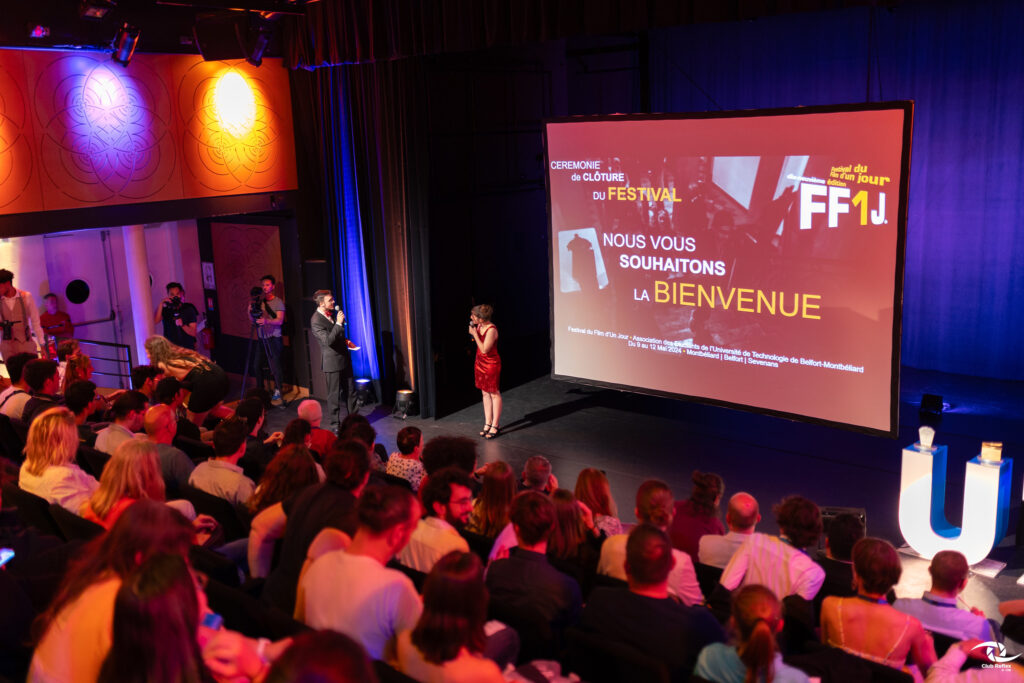 cérémonie de clôture du festival FF1J. Une salle type amphithéâtre remplie. Une femme et un homme échangent