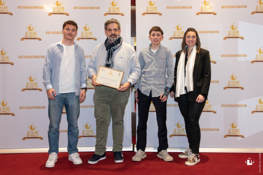 Quatre personnes debout sur un tapis rouge, posant pour une photo officielle lors de la cérémonie "JE FILME MA FORMATION".