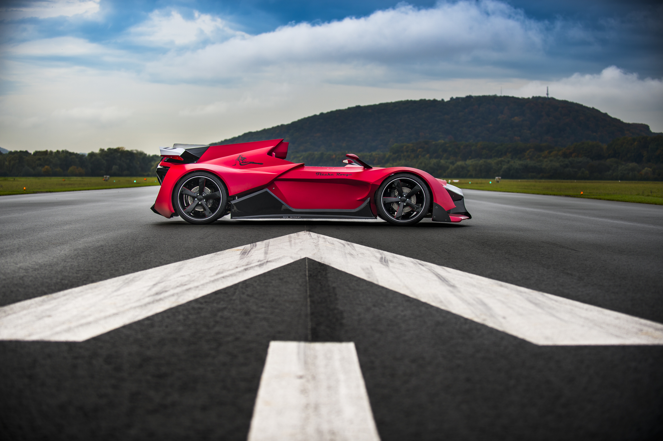 Une voiture de couleur rouge, sur une piste de circuit automobile