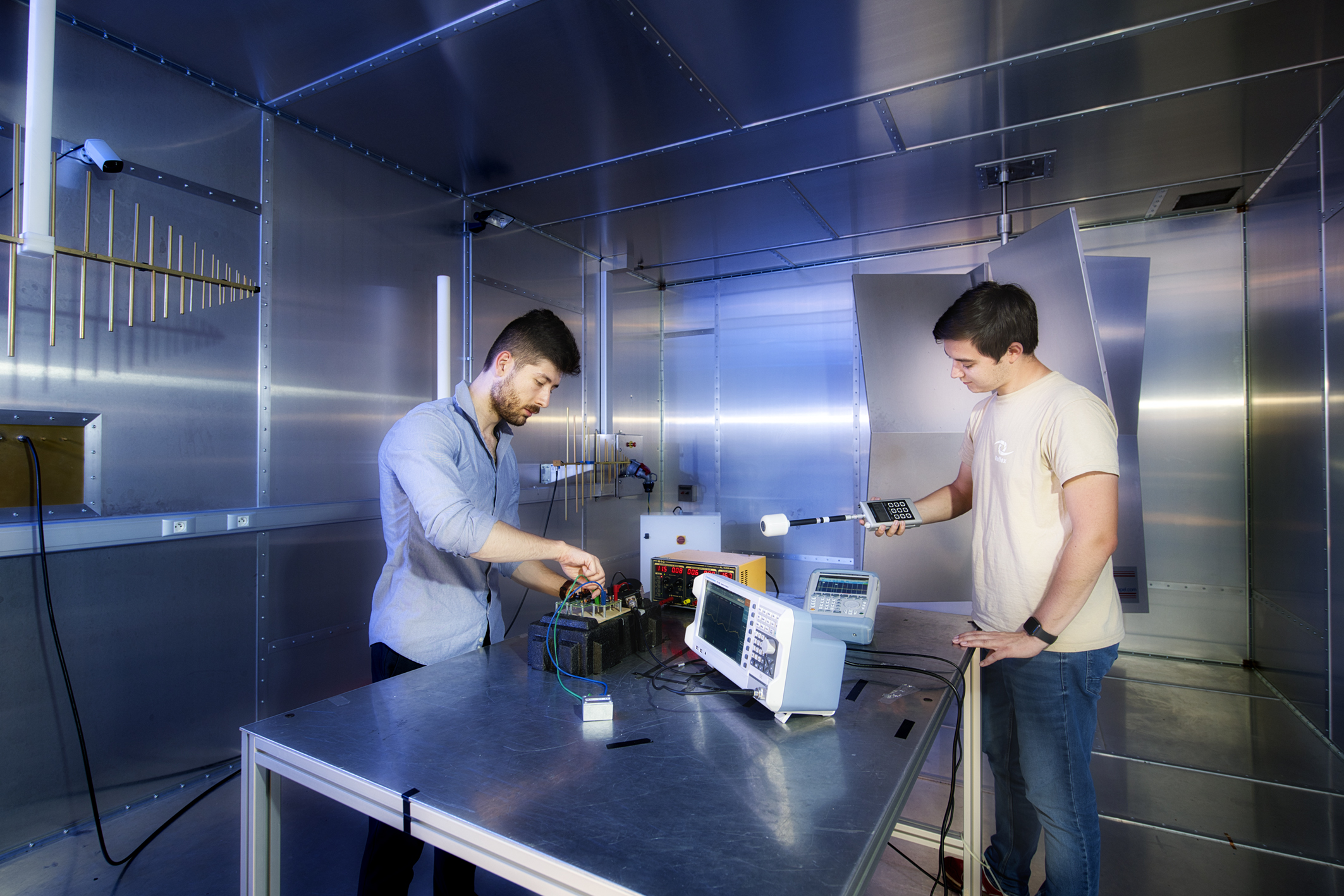Deux hommes travaillant sur un circuit électronique posé sur une table, en laboratoire