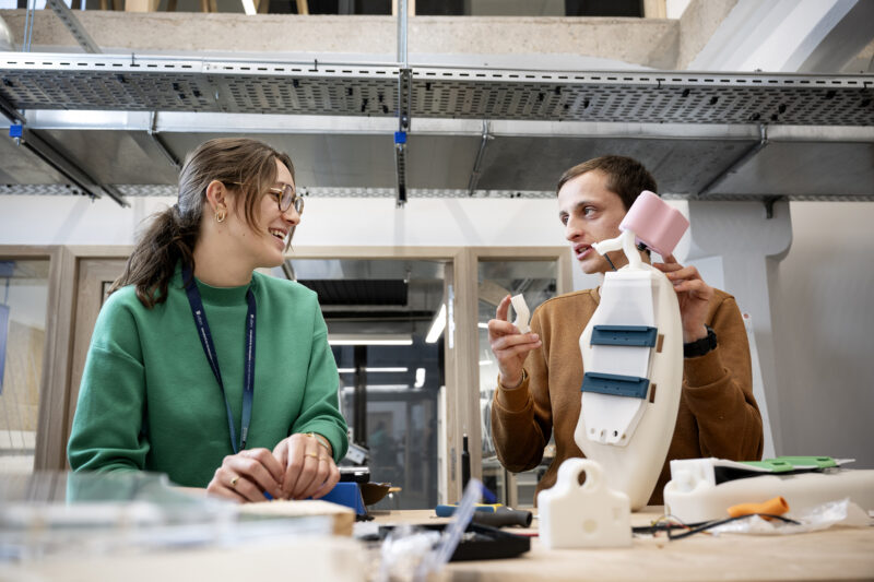 Deux étudiants, une femme et un homme, dans un laboratoire travaillant sur un projet robotique.