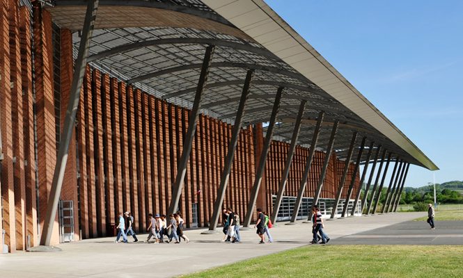 Plusieurs groupes de personnes se dirigeant à l'entrée d'un bâtiment moderne.