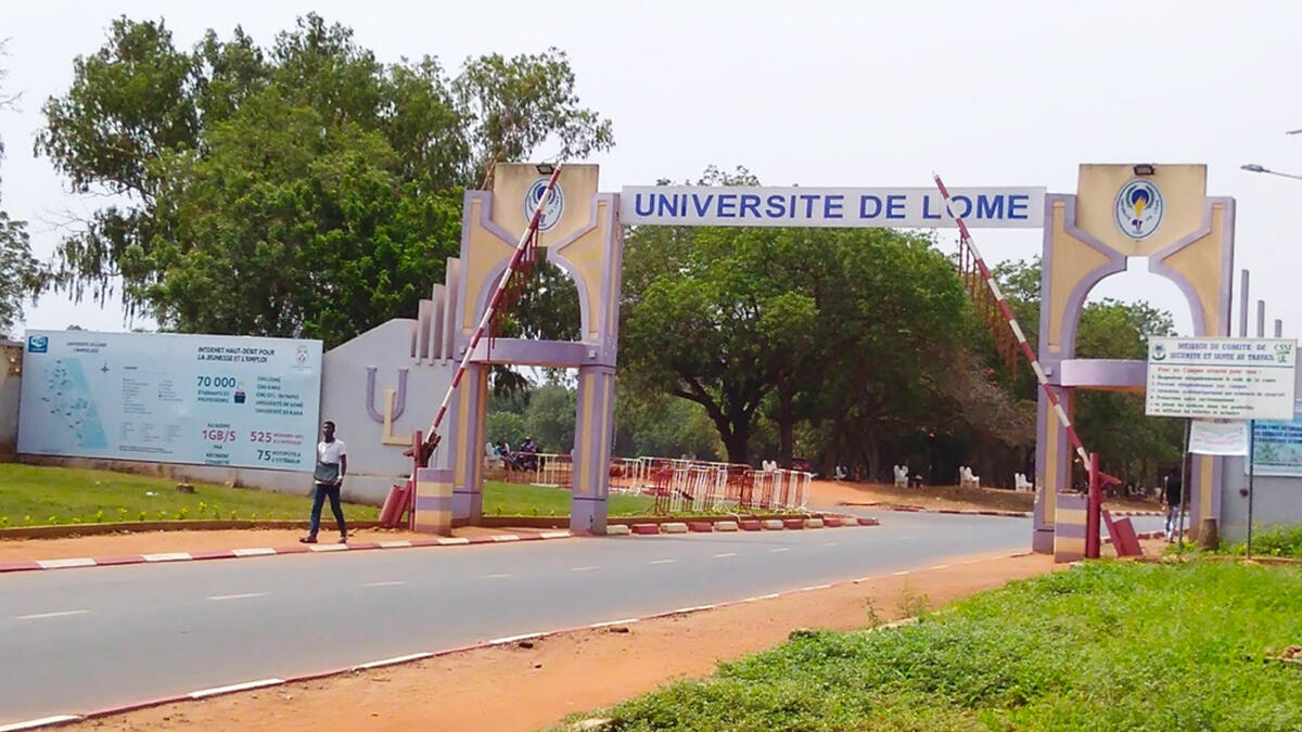 Entrée de l'Université de Lome. Les barrières sont ouvertes et un étudiant marche