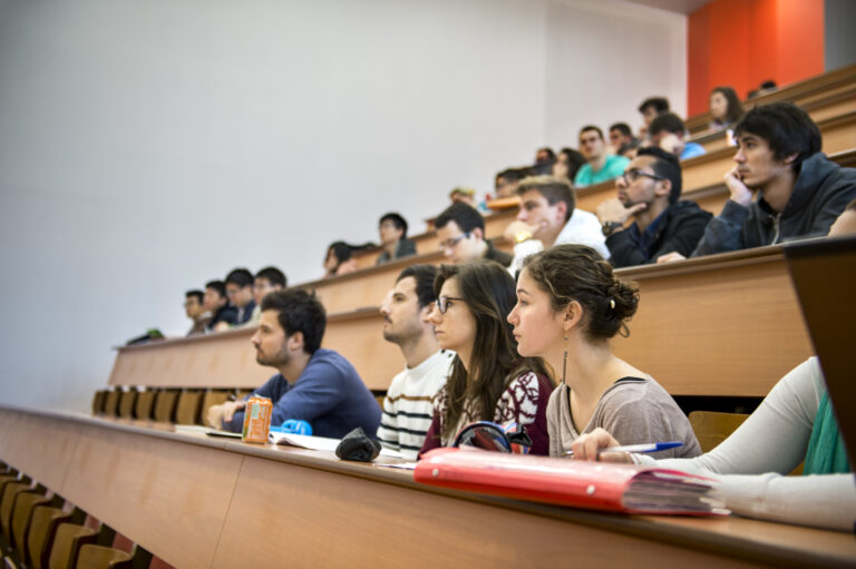 Des étudiants en amphithéâtre, écoutant un cours magistral