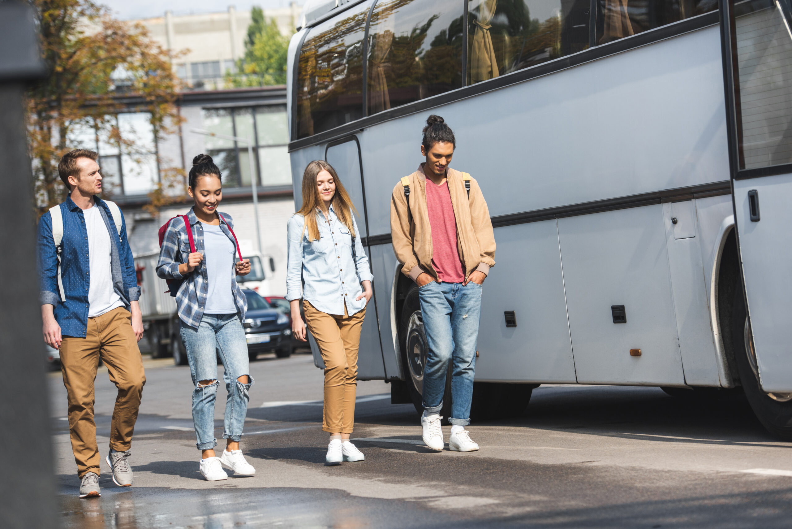 4 étudiants se déplaçant dans la rue. Un bus se trouve à leur gauche