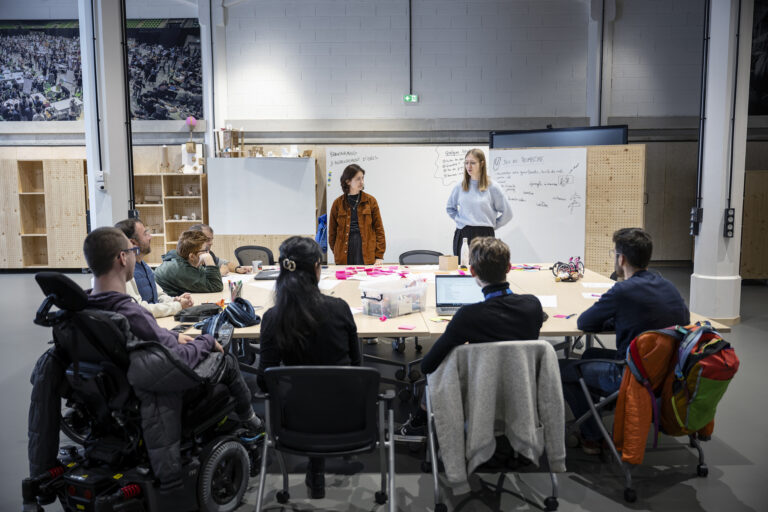Un groupe de personne assis autour d'une table travaillant pour un projet dans une pièce de travail (CrunchLab)