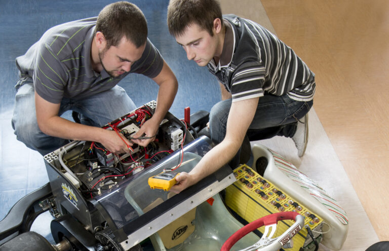 2 étudiants travaillant sur le circuit éléctrique d'une maquette de voiture