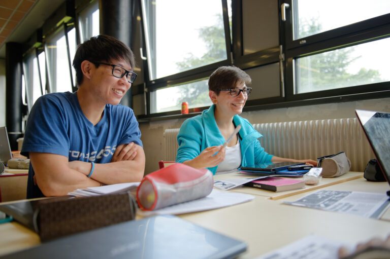 Deux étudiants souriants travaillant en groupe, dans une salle de classe